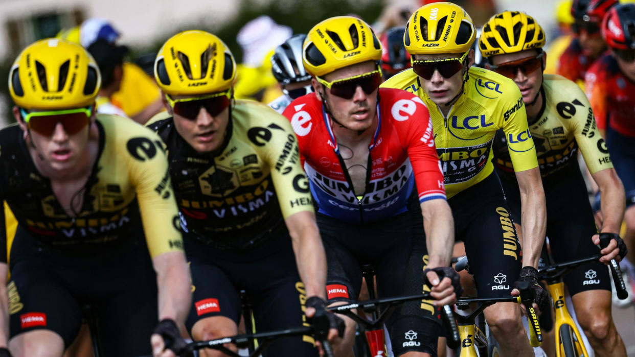  A group of five professional cyclists mid-race, wearing bright yellow helmets and lycra suits, in preparation for the Men's 2024 Santos Tour Down Under . 