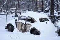 Snow left by a fast-moving winter storm is draped over the charred remains of vehicles destroyed by wildfires Thursday, Jan. 6, 2022, in Superior, Colo.Colorado authorities said Thursday, that last week's wildfires caused $513 million in damage and destroyed 1,084 homes and structures. (AP Photo/David Zalubowski)