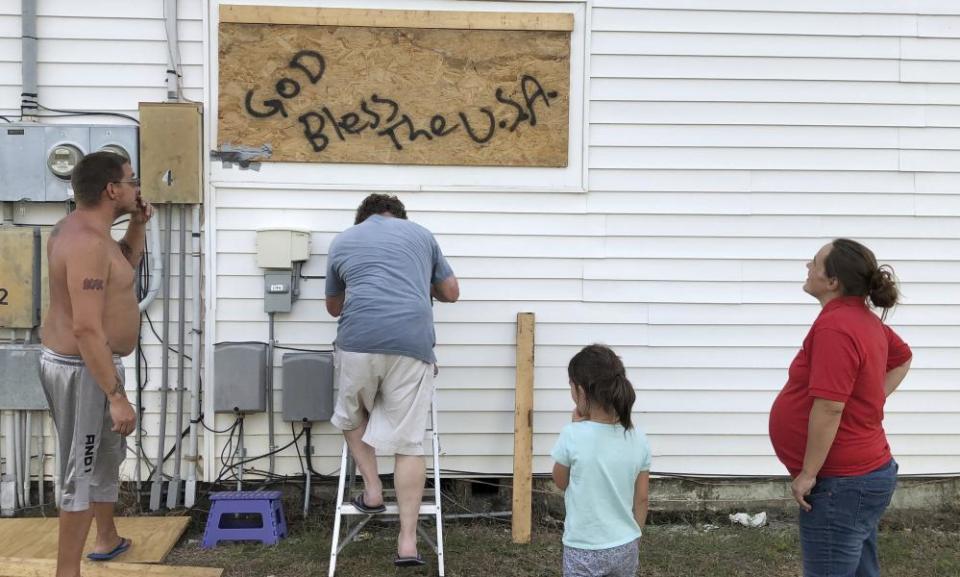 Mercedes O’Neill and her boyfriend, Kelly Johnson, and neighbor Shawn Dalton put plywood on the window of their home in North Myrtle Beach, South Carolina.