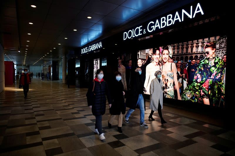 FILE PHOTO: People wearing face masks walk past a Dolce & Gabbana store at a shopping mall in Wuhan