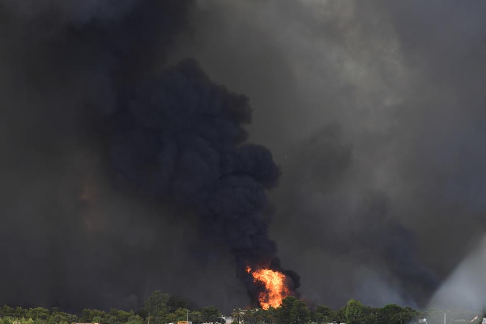 Flames burn near buildings outside an Air Base in Tatoi area, northern Athens, Greece, Tuesday, Aug. 3, 2021. Greece Tuesday grappled with the worst heatwave in decades that strained the national power supply and fueled wildfires near Athens and elsewhere in southern Greece. As the heat wave scorching the eastern Mediterranean intensified, temperatures reached 42 degrees Celsius (107.6 Fahrenheit) in parts of the Greek capital. (AP Photo/Michael Varaklas)