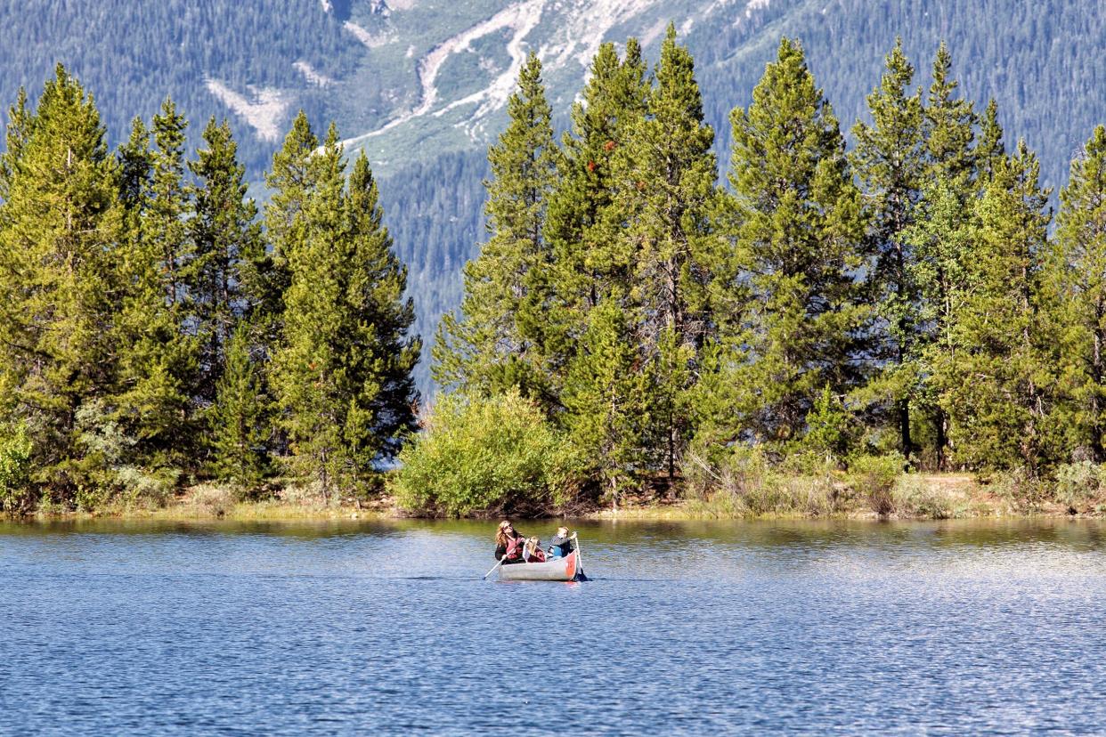 senior man and woman paddling a canoe on Jackson lake in Grand Teton National Park