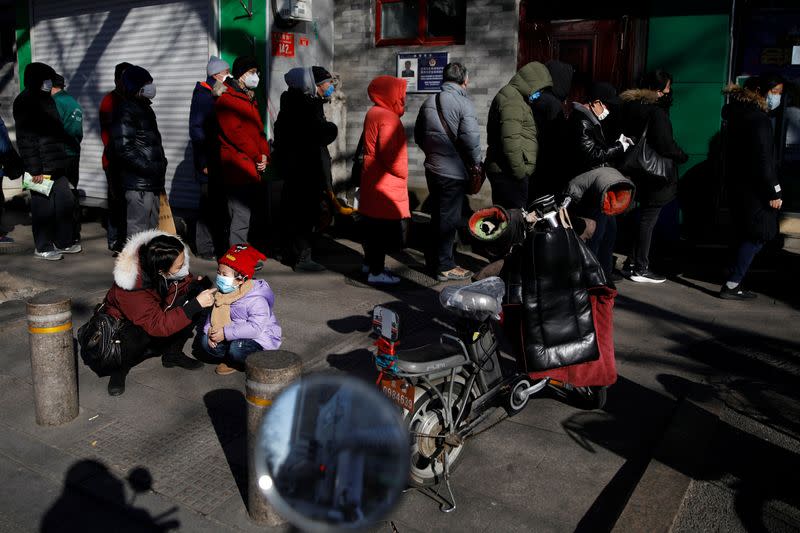 People wearing face masks line up outside a pharmacy as the country is hit by an outbreak of the new coronavirus, in Beijing