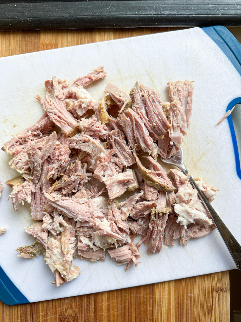 shredding the pre-cooked carnitas on a cutting board