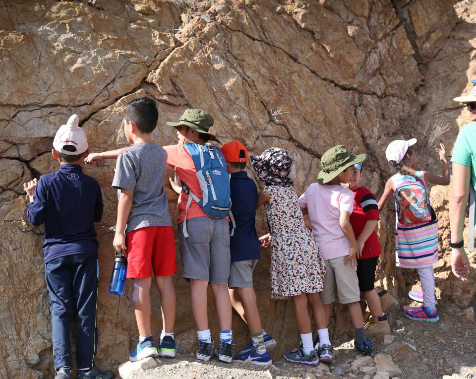 Children look at traces of dinosaur tracks on the face of a rock formation Sunday. 