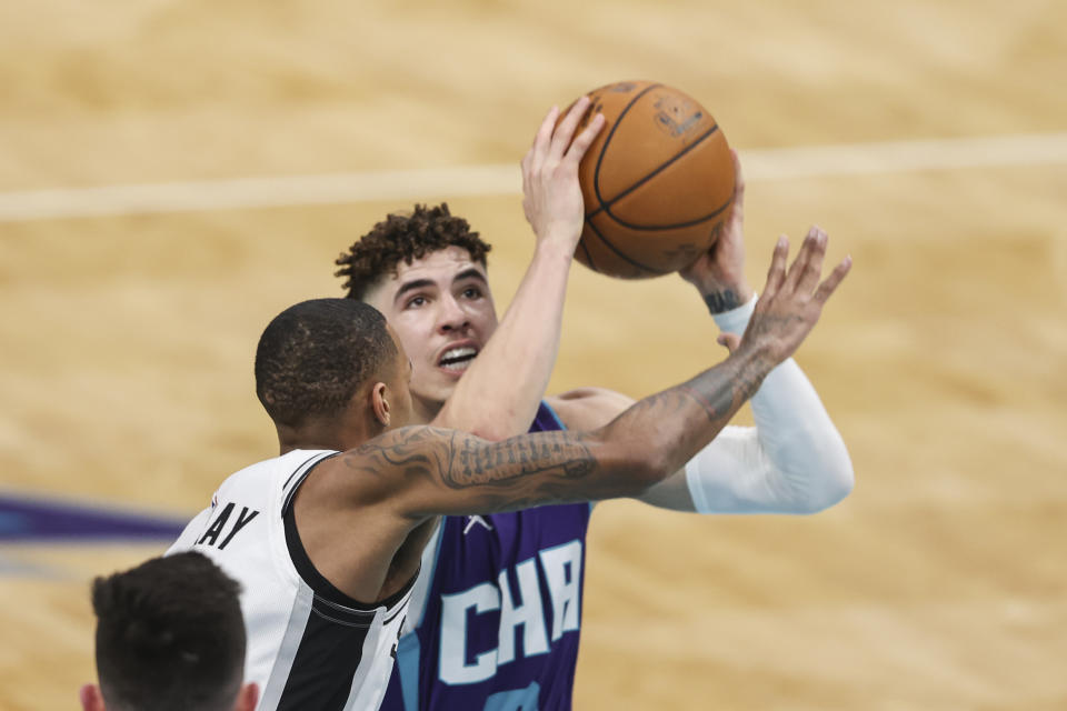 Charlotte Hornets guard LaMelo Ball, right, shoots against San Antonio Spurs guard Dejounte Murray during the first half of an NBA basketball game in Charlotte, N.C., Sunday, Feb. 14, 2021. (AP Photo/Nell Redmond)