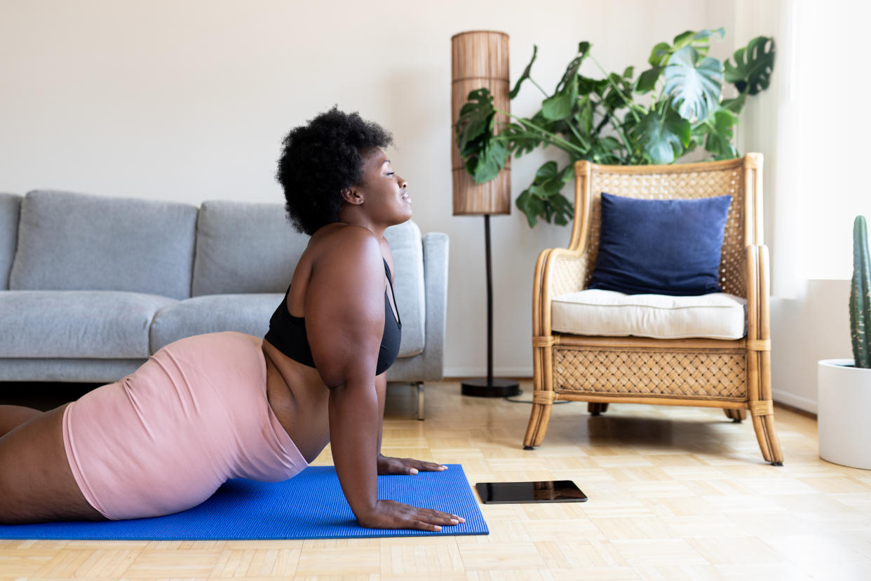 Woman doing yoga exercise on mat at home. 2024's health and wellness trends have been released. (Getty Images)