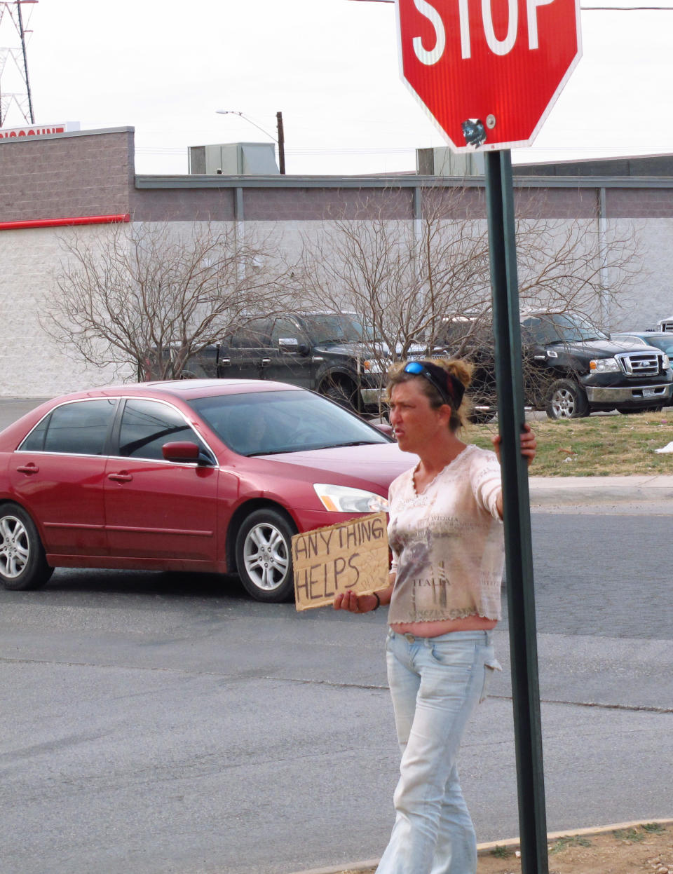 In this photo from Feb. 24, 2014, homeless woman, who gave her name as only Katt, stands on a street corner in Midland, Texas, trying to get donations from motorists. Two Midland police officers were disciplined with a three-day suspension recently for having a contest to see who could confiscate the most signs from homeless people. (AP Photo/Betsy Blaney)