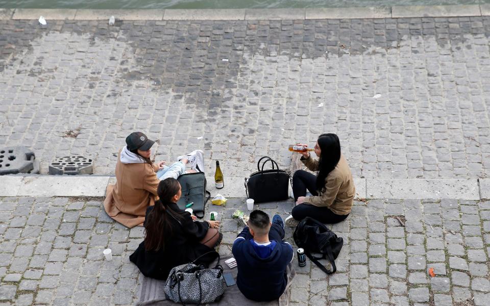 People gather on the banks of the Seine river  - Getty