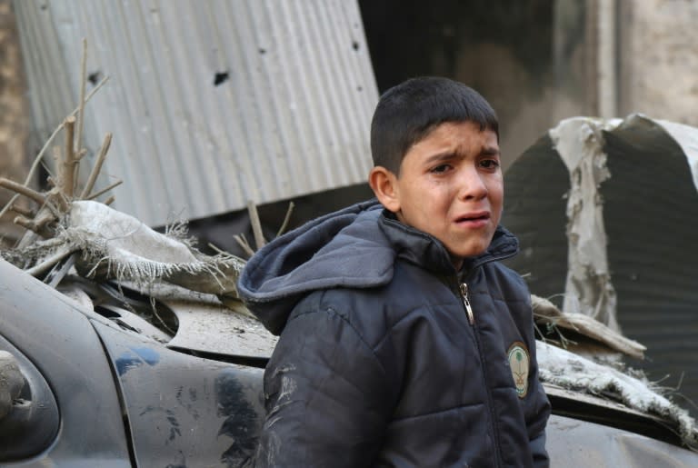 A Syrian boy cries as he stands next to a building hit by an air strike on the village of Maaret al-Numan, in the country's northern province of Idlib, on December 4, 2016