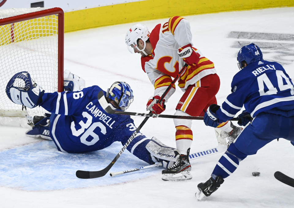 Toronto Maple Leafs goaltender Jack Campbell (36) poke-checks Calgary Flames forward Derek Ryan (10) as Maple Leafs defenseman Morgan Rielly (44) keeps close during second-period NHL hockey game action in Toronto, Saturday, March 20, 2021. (Nathan Denette/The Canadian Press via AP)