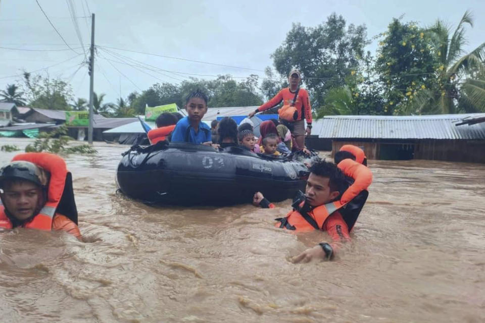 In this photo provided by the Philippine Coast Guard, rescuers use boats to evacuate residents from flooded areas due to Tropical Storm Nalgae at Parang, Maguindanao province, southern Philippines on Friday Oct. 28, 2022. Floodwaters rapidly rose in many low-lying villages, forcing some villagers to climb to their roofs, where they were rescued by army troops, police and volunteers, officials said. (Philippine Coast Guard via AP)