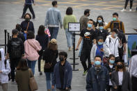 People wear face masks to protect against the spread of the new coronavirus as they walk through a temperature checkpoint at an outdoor shopping area in Beijing, Saturday, May 9, 2020. North Korean state media reported on Friday that leader Kim Jong Un sent a personal message to Chinese President Xi Jinping to praise what he described as China's success in getting its COVID-19 epidemic under control. (AP Photo/Mark Schiefelbein)