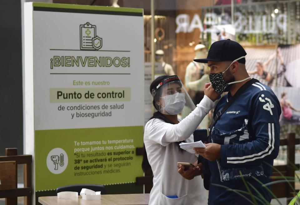 In this June 9, 2020 photo, a nurse measures the body temperature of a shopper at the El Tesoro mall, amid the new coronavirus pandemic, in Medellin, Colombia. The metropolis recently went five weeks without a single COVID-19 death. (AP Photo/Luis Benavides)