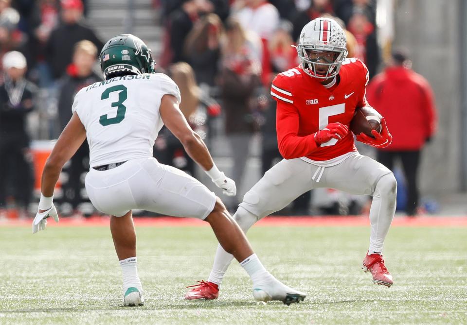 Ohio State Buckeyes wide receiver Garrett Wilson (5) runs around Michigan State Spartans safety Xavier Henderson (3) during the second quarter of the NCAA football game at Ohio Stadium in Columbus on Saturday, Nov. 20, 2021. 