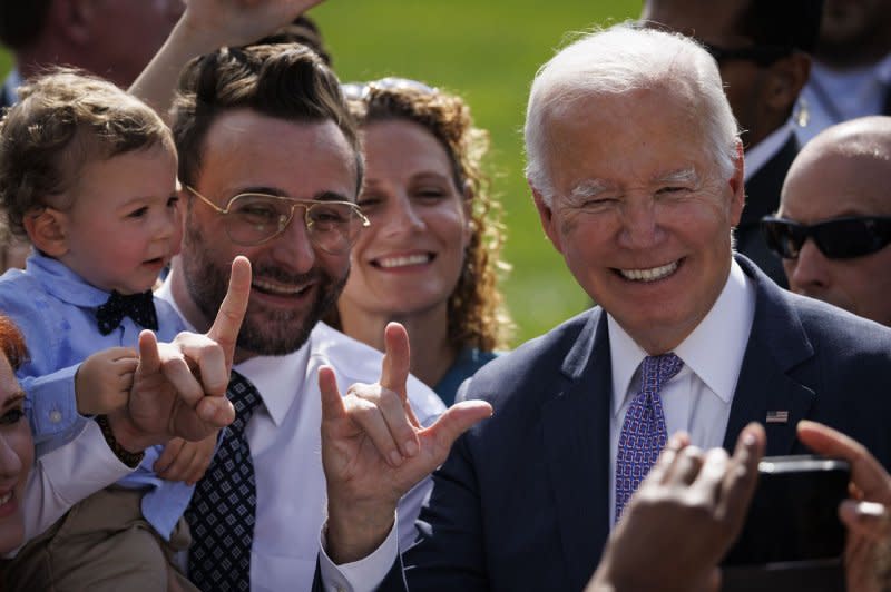 President Joe Biden signs " I love you" in American Sign Language on Monday while taking photos with guests during an event to celebrate the Americans with Disabilities Act (ADA) on the South Lawn of the White House. Photo by Ting Shen/UPI