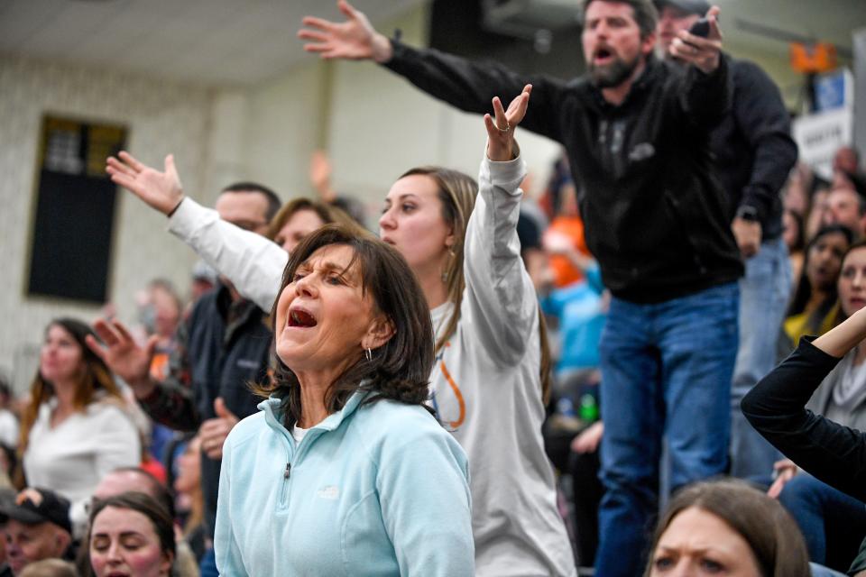 Fans yell at a referee during a high school basketball game.