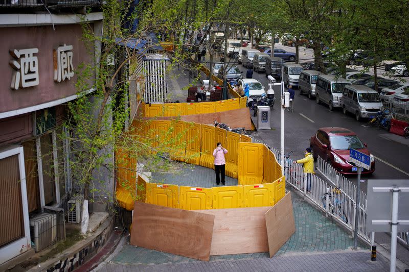 A woman wearing a face mask is seen at a residential area blocked by barriers in Wuhan