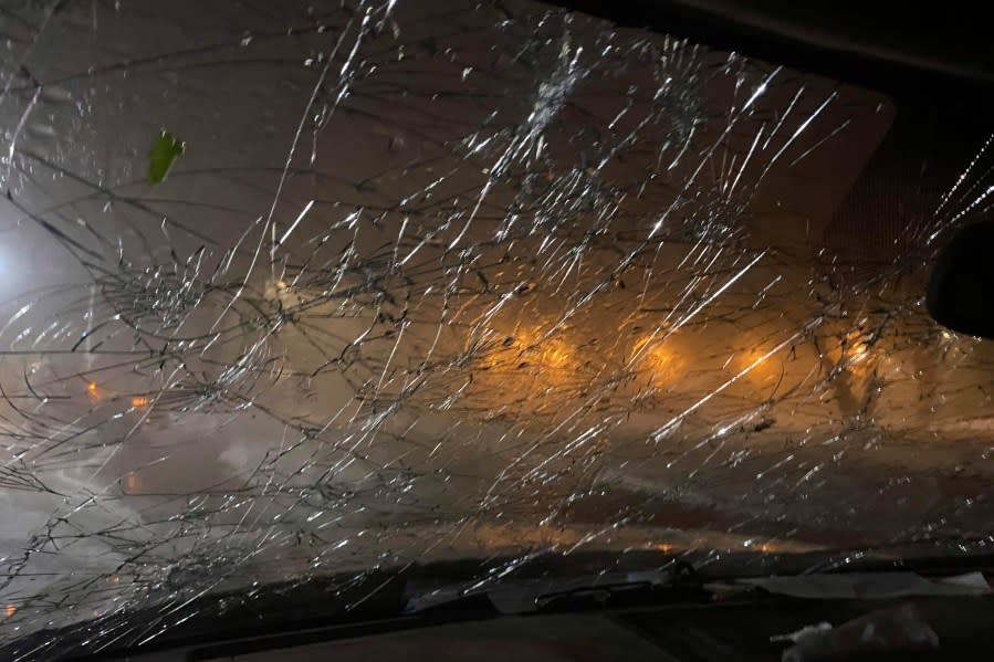 This image provided by JJ Unger, shows hail damage to the window of vehicle, Monday night, May 20, 2024, in Yuma, Colo. Residents in the small city in northeastern Colorado were cleaning up Tuesday after hail the size of baseballs and golf balls pounded the community, with heavy construction equipment and snow shovels being used to clear hail that had piled up knee-deep the night before. (JJ Unger via AP)