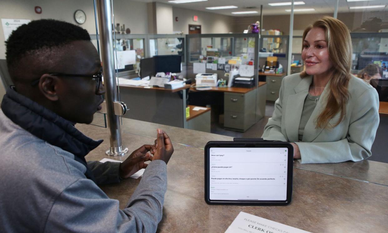 Samuel Uwizeyimana (left) and Rachel Scaperotta (right), both employees with the Minnehaha County Clerk of Courts, have a conversation in Spanish and English to demonstrate how a live interpreter service through Certified Languages International works. The device is part of a pilot program to improve language access in the state court system.
