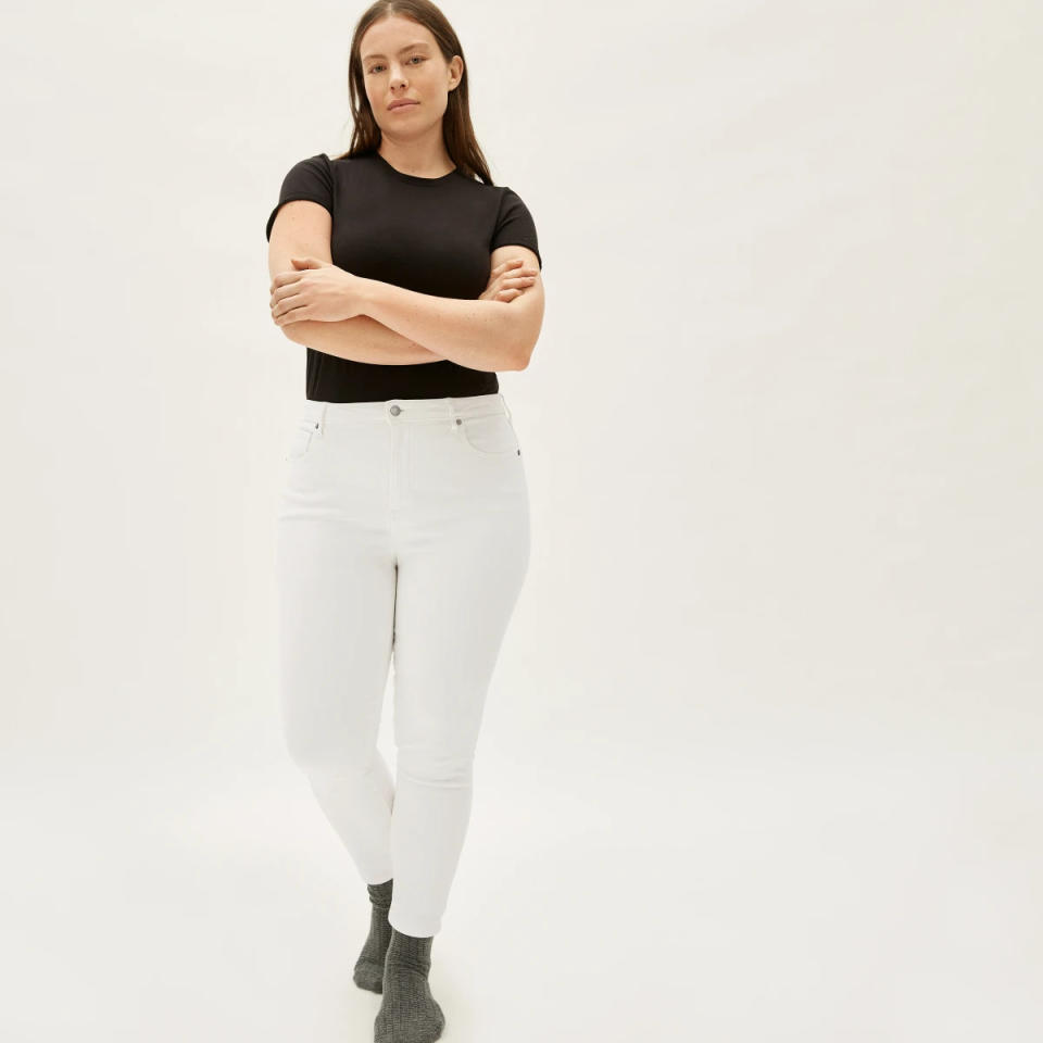 Model wears The Curvy Authentic Stretch High-Rise Skinny Jean in white with a black T-shirt. Image via Everlane.