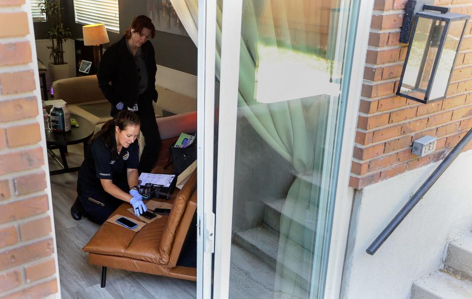 Unified Police forensic investigator Nicole Garrett documents evidence during a home search after two people were taken into custody for their suspected involvement in an odometer scam in South Salt Lake on Wednesday, Aug. 9, 2023. Unified Police technical services secretary Abby Reynolds watches. | Kristin Murphy, Deseret News