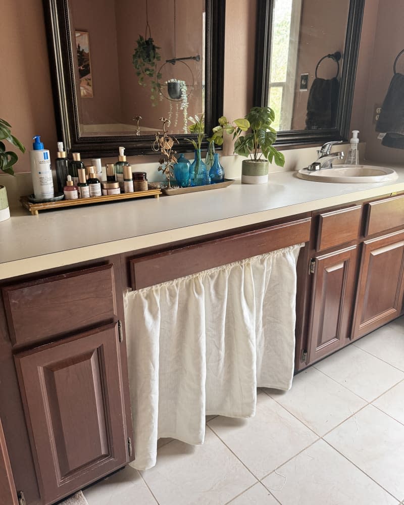 Bathroom with white curtain hanging inbetween sinks