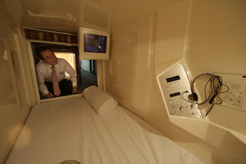 In this Monday, Oct. 29, 2012 photo, manager Akiyoshi Kaneko peers inside of a room at the Capsule & Sauna Century Shibuya in Tokyo. The capsule concept has been around for at least 30 years, starting out as lodging for businessmen working or partying late who missed the last train home and needed a cheap place to crash. But budget travelers and other folks curious about a unique lodging experience use them too. (AP Photo/Shizuo Kambayashi)