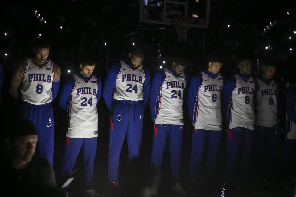 Philadelphia 76ers stand during a tribute to Kobe Bryant, before the team's NBA basketball game against the Golden State Warriors on Tuesday, Jan. 28, 2020, in Philadelphia. Bryant died along with his daughter and seven other people during helicopter crash Sunday. (Steven M. Falk/The Philadelphia Inquirer via AP)