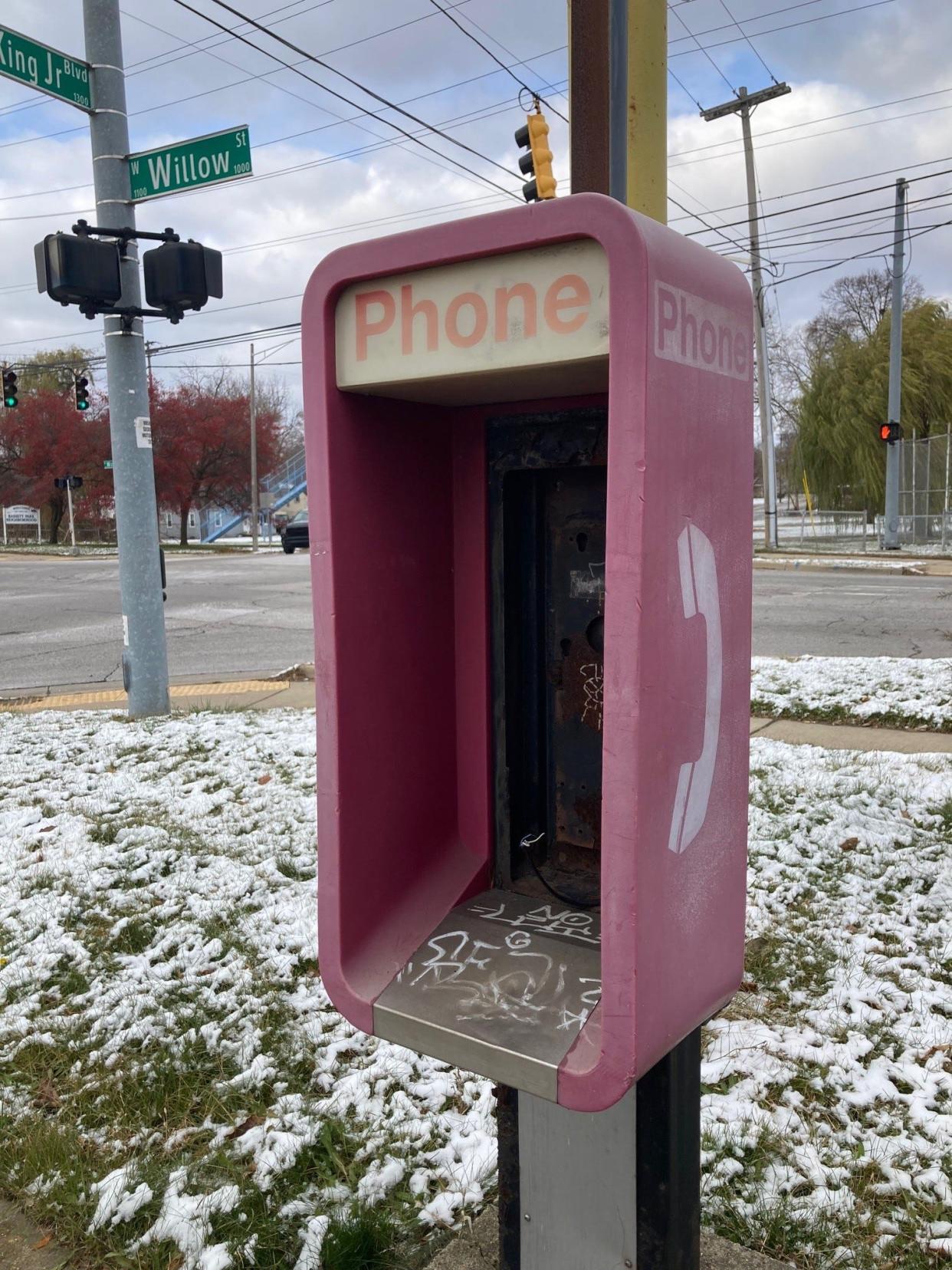 An empty pay phone box stands outside a restaurant in north Lansing. Actual working pay phones are increasingly difficult to find.