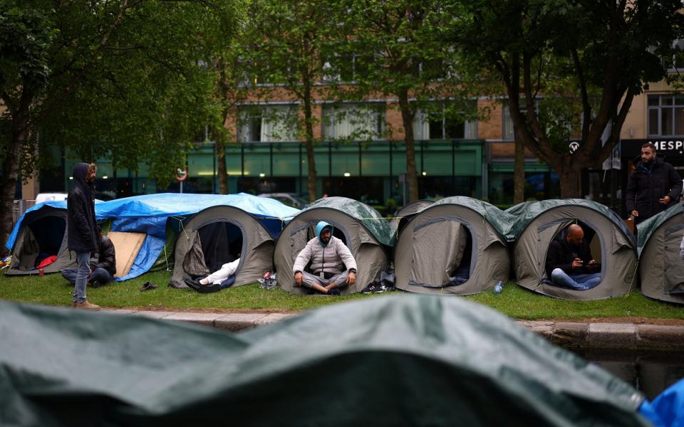 Asylum seekers look out from tents in a makeshift camp, set up by migrants, along the banks of the Grand Canal in Dublin