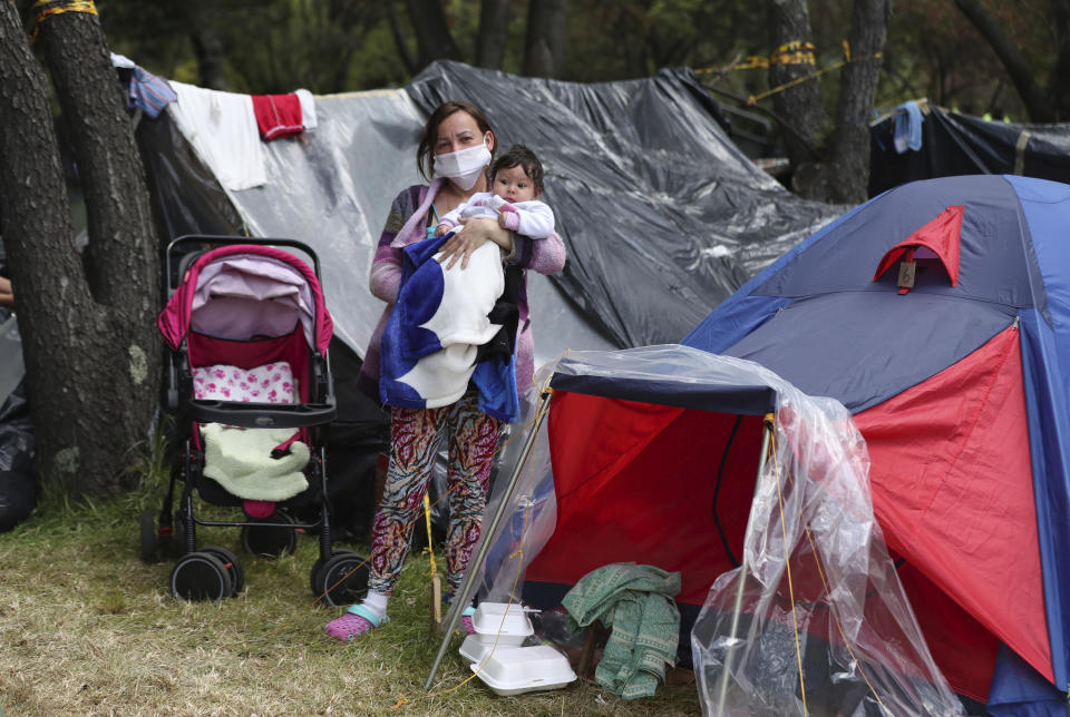 Jessica Flores posa con su hijo Luisiany en el exterior de su tienda, en un parque donde viven junto a otros migrantes venezolanos desempleados desde finales de mayo, cerca de la estación de autobuses de Bogotá, Colombia, el 10 de junio de 2020. (AP Foto/Fernando Vergara)