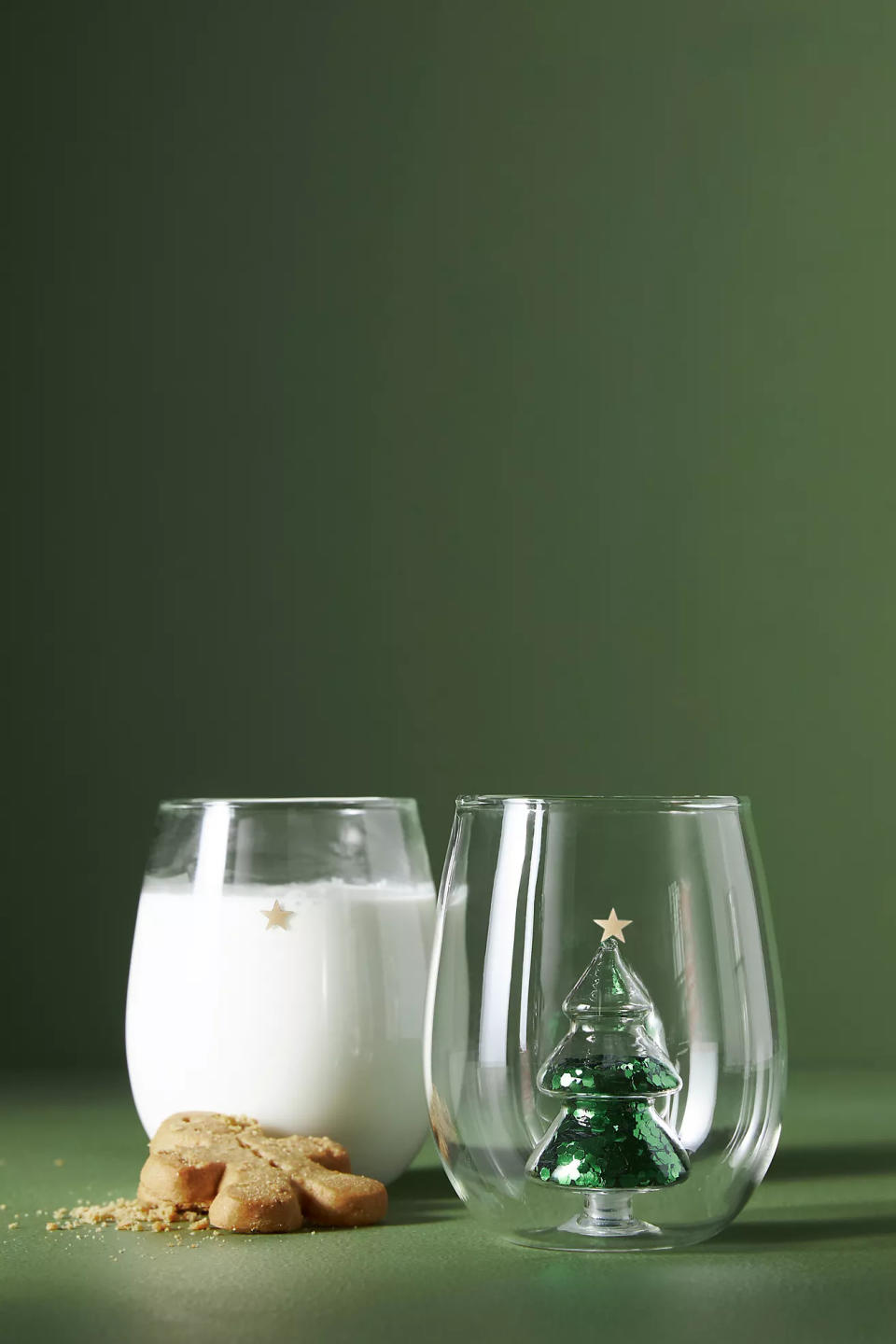 two wine glasses, one filled with milk, beside a cookie