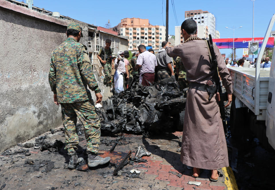 Security personnel a vehiclestand amid the wreckage of a vehicle at the site of a deadly car bomb attack that targeted two senior government officials, who survived, security officials said, in the port city of Aden, Yemen, Sunday, Oct. 10, 2021. Aden has been the seat of the internationally recognized government of President Abed Rabbo Mansour Hadi since the Iranian-backed Houthi rebels took over the capital, Sanaa, triggering Yemen’s civil war. (AP Photo/Wael Qubady)