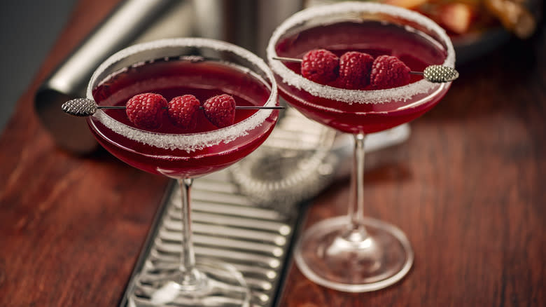 Two cocktails with raspberry garnish