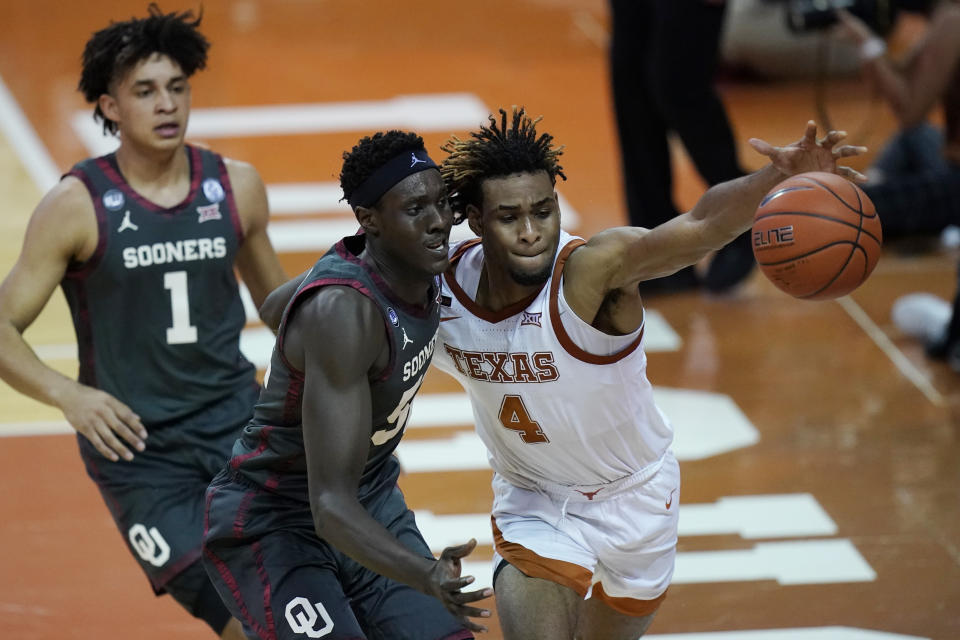 Texas forward Greg Brown (4) and Oklahoma forward Kur Kuath, center, chase the ball during the first half of an NCAA college basketball game Tuesday, Jan. 26, 2021, in Austin, Texas. (AP Photo/Eric Gay)