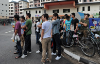 Foreign workers wait for their transportation to work outside their dormitory in Singapore on November 26, 2012. More than 100 mainland Chinese bus drivers in Singapore refused to work in a rare case of labour mass action in the city-state. AFP PHOTO/ROSLAN RAHMAN