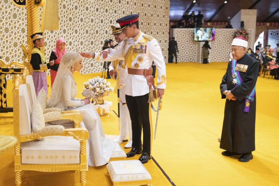In this photo released by Brunei's Information Department, Brunei's Prince Abdul Mateen, center, and bride Anisha Rosnah, left, attend their wedding reception at Istana Nurul Iman in Bandar Seri Begawan, Brunei Sunday, Jan. 14, 2024. (Brunei's Information Department via AP)