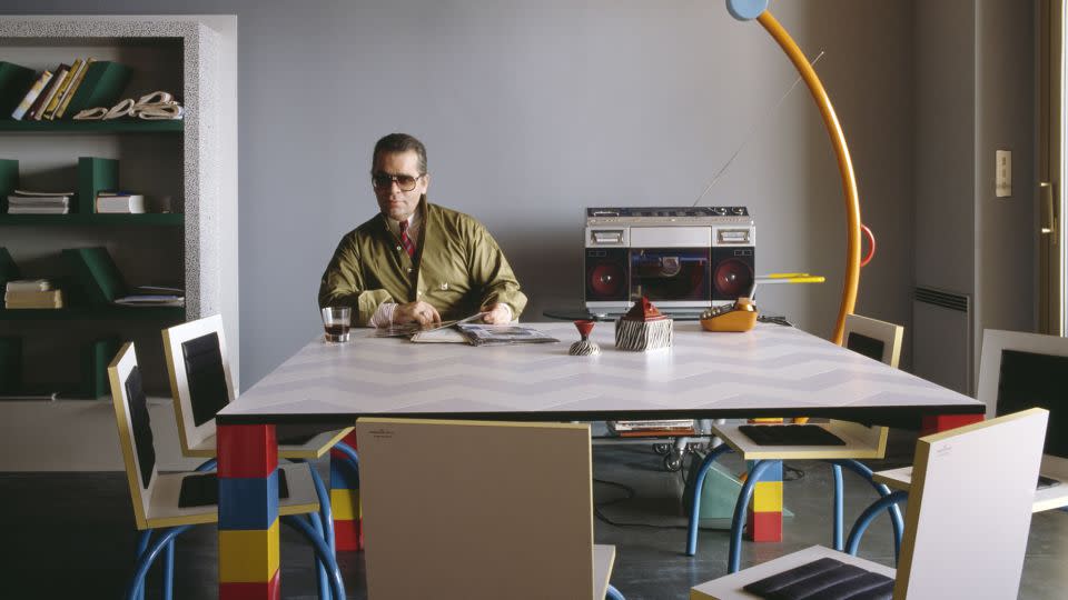 Lagerfeld poses at the über-modern dining table in his Monte Carlo apartment, which he purchased in the early 19080s, a Diet Coke-filled glass (the designer was well-known for his love of the soda) at hand. - Jacques Schumacher