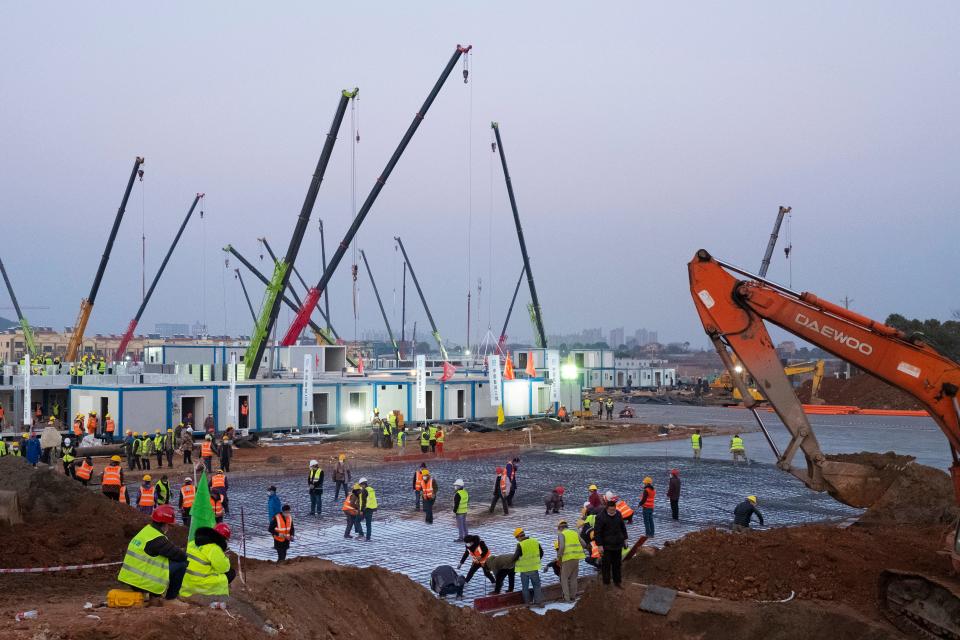 Construction workers labor at the site of the Huoshenshan temporary field hospital being built in Wuhan.