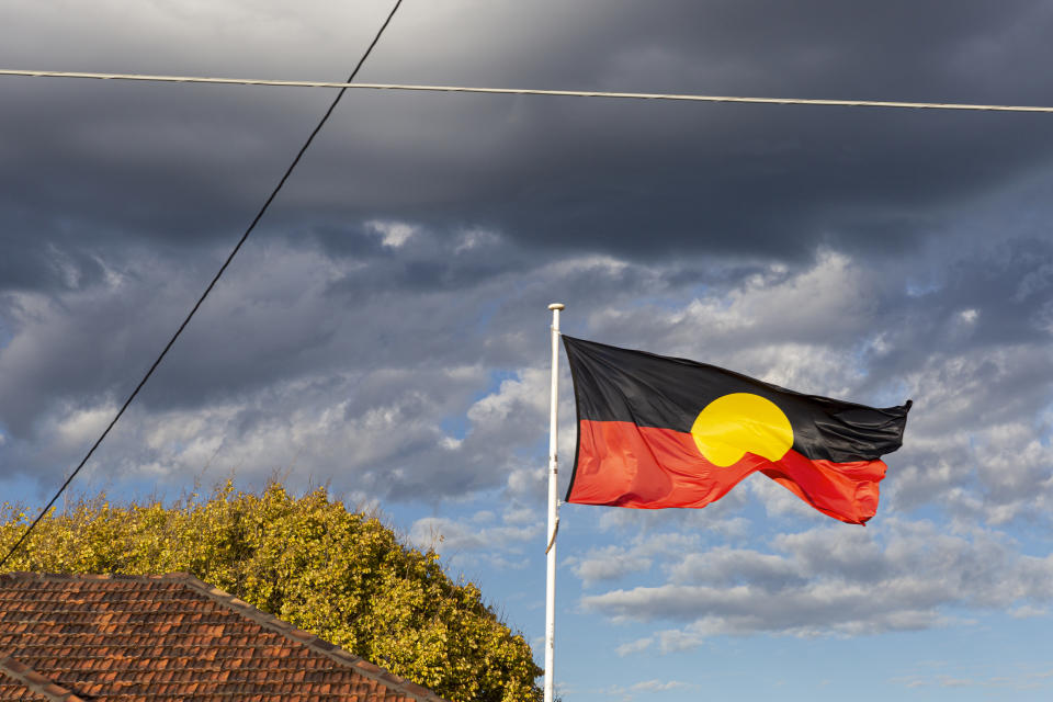 Aboriginal flag flying high above community centre in suburban neighbourhood.