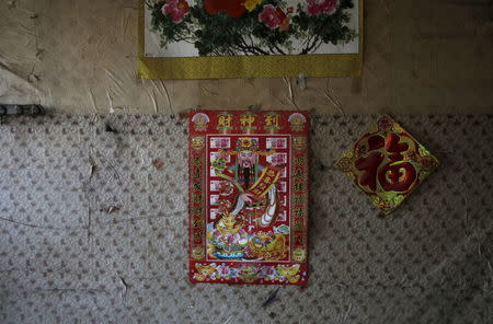 A poster of the Chinese God of Fortune is seen on a wall inside a deserted dormitory near a closed brick factory, on the outskirts of Beijing, China, January 18, 2016.. REUTERS/Jason Lee