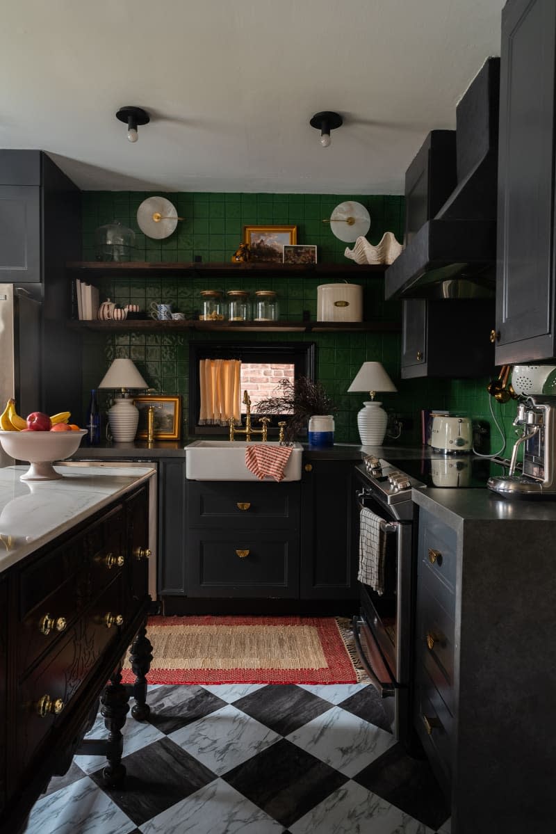 Kitchen with black cabinets and green tiled backsplash.