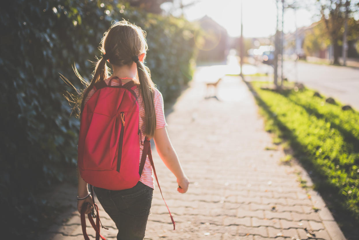 Girls wearing red backpack walking to school