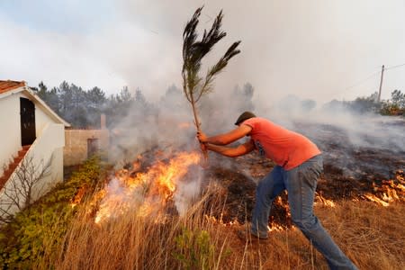 Villagers help to put out a forest fire at the small village of Colos