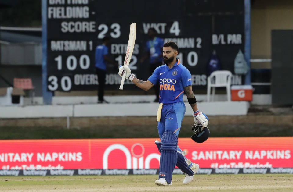 India captain Virat Kohli raises his bats to celebrate reaching a century during the third One-Day International cricket match West Indies in Port of Spain, Trinidad, Wednesday, Aug. 14, 2019. India won by 6 wickets, with 15 balls remaining. (AP Photo/Arnulfo Franco)