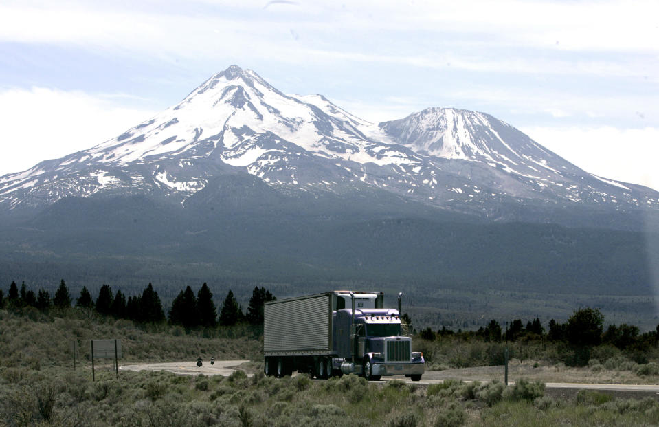 FILE - In this June 19, 2008 file photo, a truck drives past Mt. Shasta, near Weed, Calif. California regulators will hold a public hearing on Thursday, Dec. 12, 2019 about whether to require a certain percentage of truck sales to be zero emission vehicles. California has some of the worst air quality in the nation, largely driven by pollution from cars and trucks. (AP Photo/Rich Pedroncelli,file)