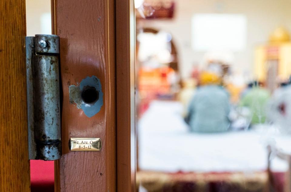 A bullet hole remains with a plaque inscribed "We Are One" on the door frame of the Sikh Temple of Wisconsin in Oak Creek.