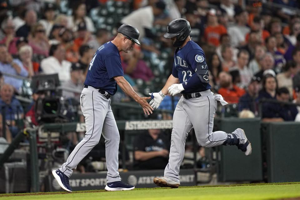 Seattle Mariners' Ty France (23) celebrates with third base coach Manny Acta after hitting a home run against the Houston Astros during the fourth inning of a baseball game Wednesday, June 8, 2022, in Houston. (AP Photo/David J. Phillip)