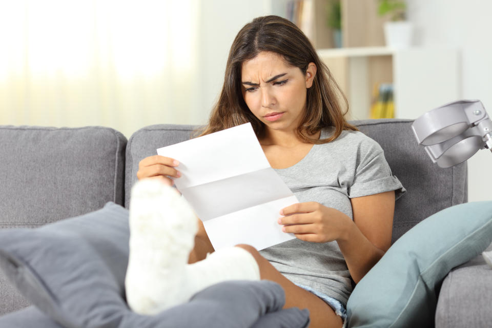 Worried woman reading a letter sitting on a couch in the living room at home